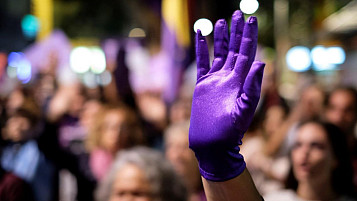 manifestación y una mano pintada de morado en primer plano